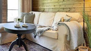 Een gezellige woonkamer met een beige bank, een ronde salontafel en een lamp.