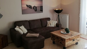 Un salón con un sofá marrón, una mesa de centro de madera y una lámpara de pie.