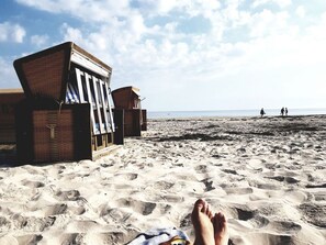 Une plage avec une structure en bois, peut-être un abri de plage, et une plage de sable parsemée d'empreintes.
