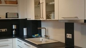 A modern kitchen with white cabinets, a black countertop, and a stainless steel range hood.