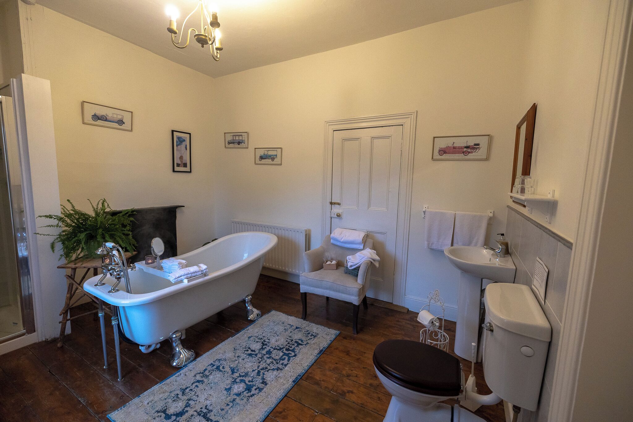 Un baño con una bañera independiente, un lavamanos, un inodoro y una silla.