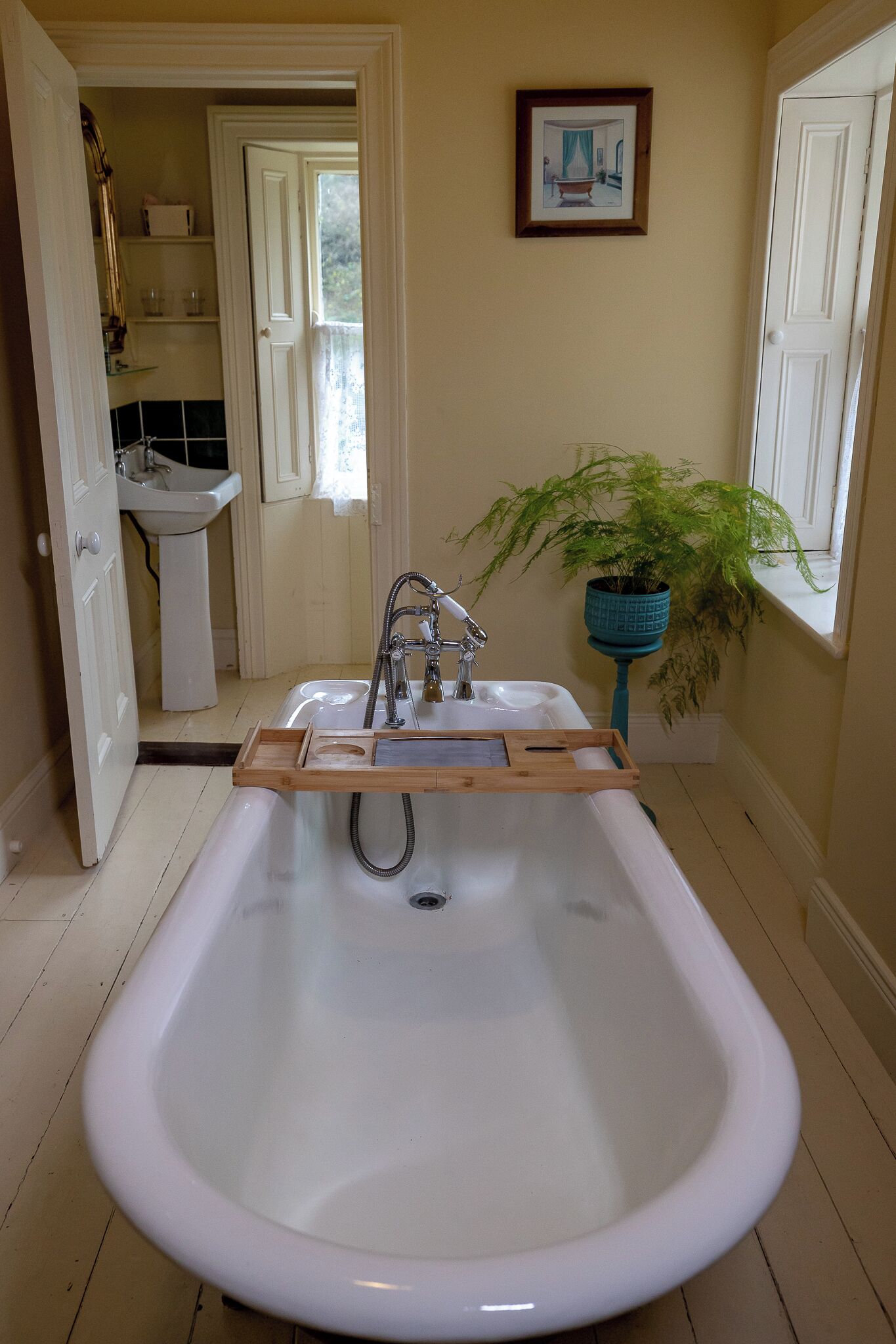 Ein Badezimmer mit einer großen Badewanne, einem Waschbecken und einer Topfpflanze.