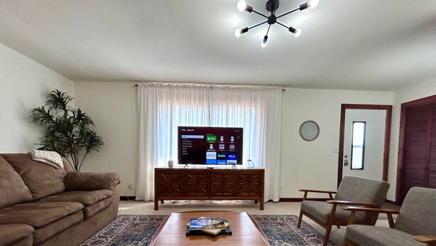 A living room with a brown sofa, a blue armchair, a wooden coffee table, and a TV on a wooden cabinet.
