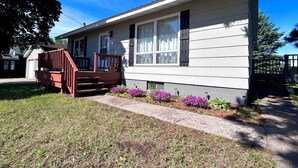 A single-story house with a front porch, a small deck, and a window with shutters.