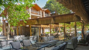 An outdoor patio with wicker furniture, a pool, and a building with a thatched roof. - Ballı Boutique Hotel & Restaurant  (Fethiye)