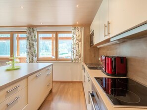 A modern kitchen with wooden cabinets, a stainless steel stove, and a window with curtains.