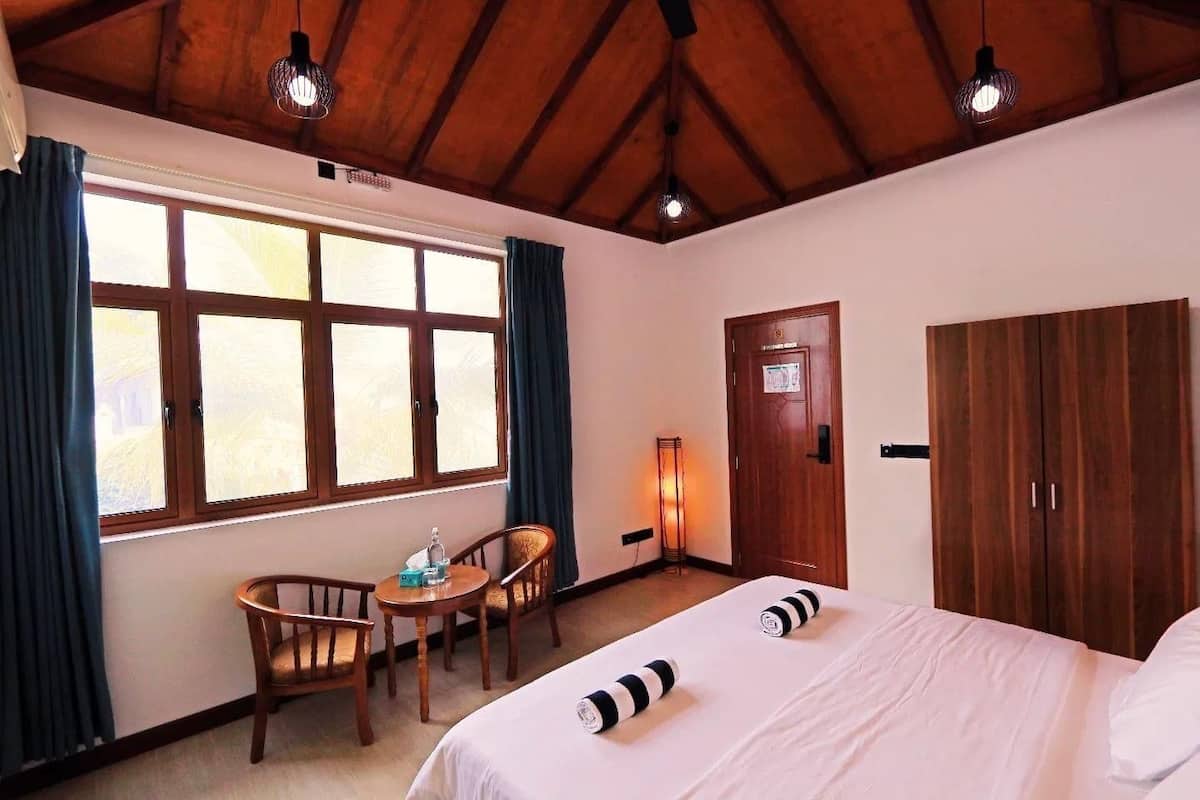 Una habitación de hotel con un ventanal grande, una cama, un escritorio y un armario.