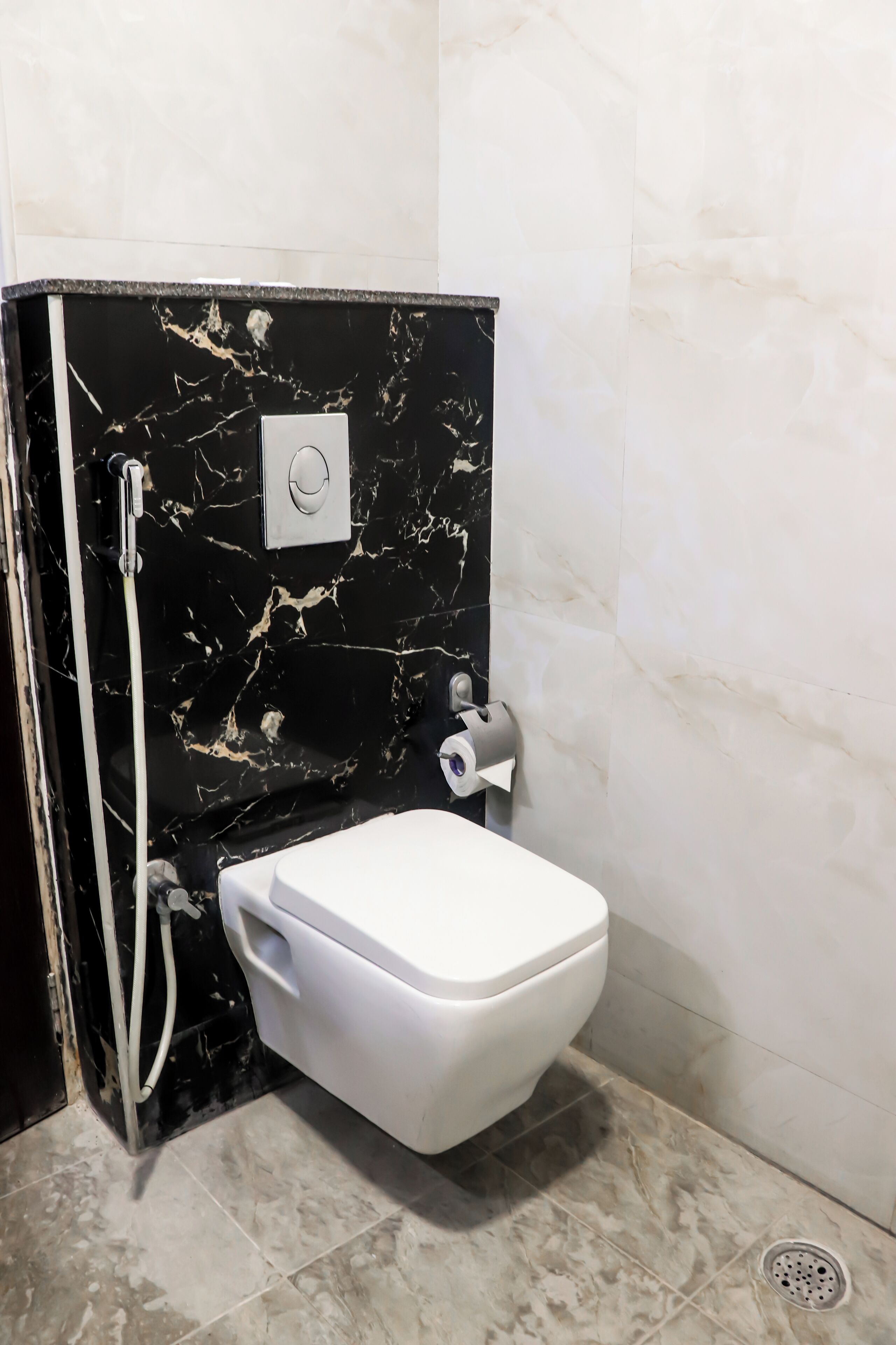 A bathroom with a toilet, a shower, and a marble wall.