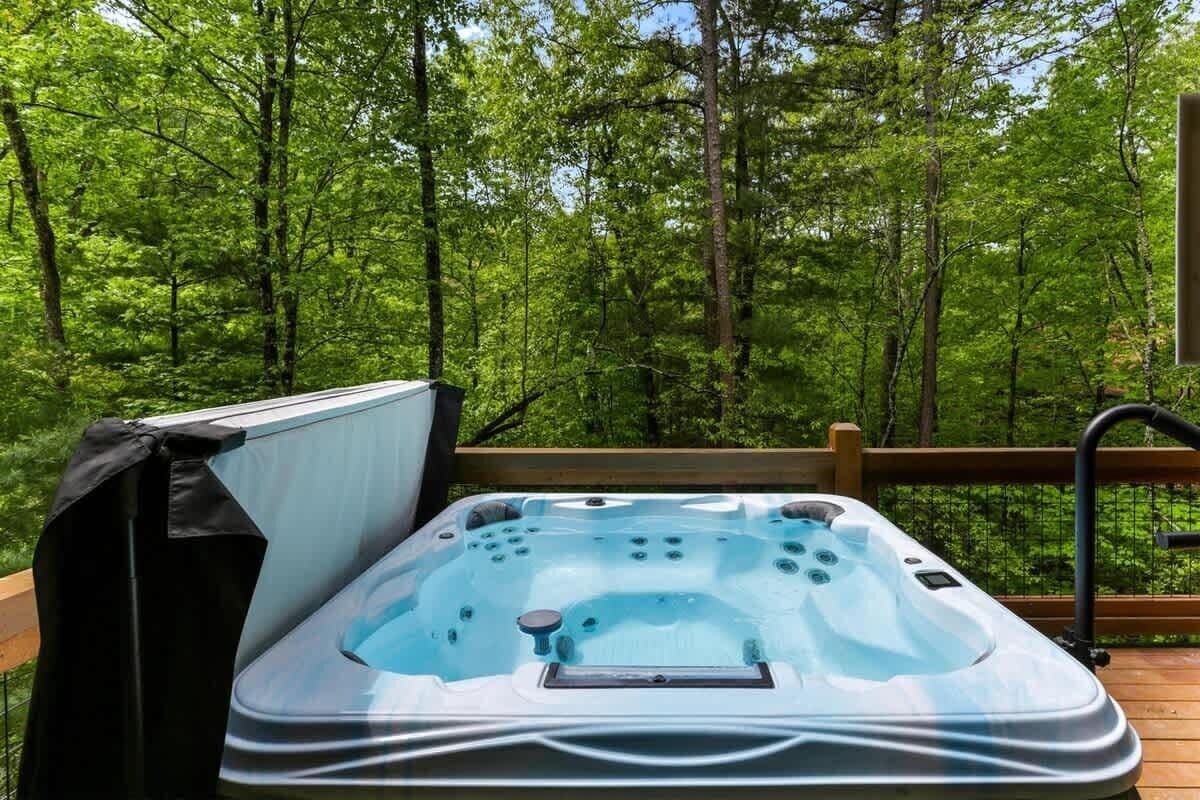 A hot tub on a wooden deck surrounded by a forest.