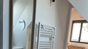 Ein modernes Badezimmer mit einem weißen Heizkörper, einem Spiegel und einem Holzschrank.