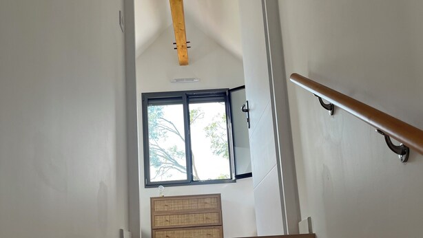 Eine Holztreppe führt zu einem Raum mit einem Fenster und einem Holzschrank.