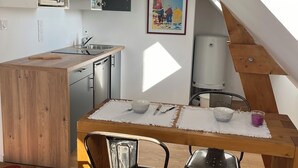 Eine Küche mit einem Holztisch, zwei Stühlen, einer Mikrowelle und einem Bild an der Wand.