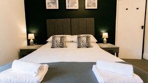 A neatly made bed with two pillows, a bedside table with a lamp, and three framed pictures on the wall. - A perfect base for exploring and relaxing, for work and leisure. Pets welcome. (Exeter)