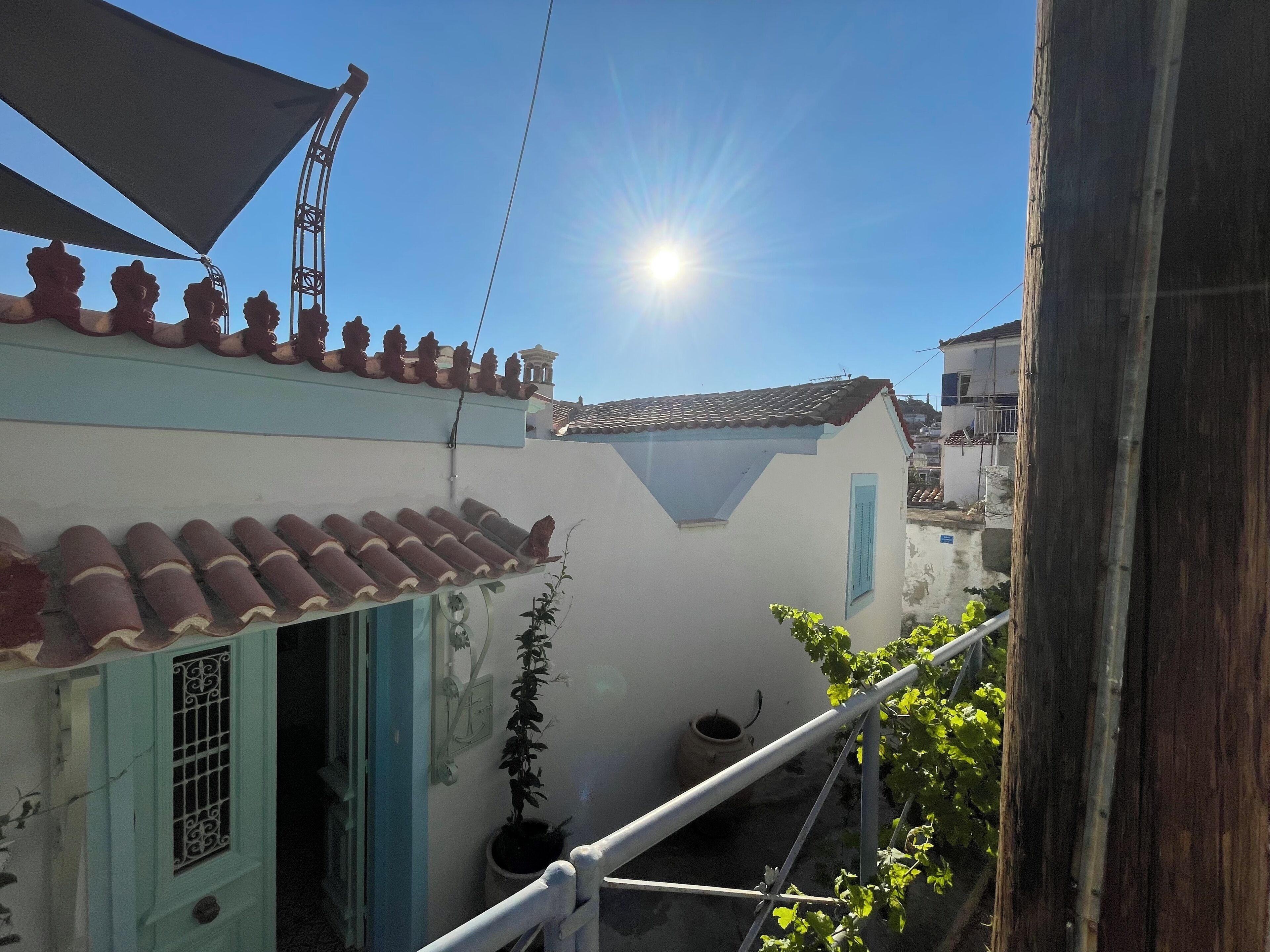 A building with a tiled roof, a small balcony with a railing, and a potted plant.