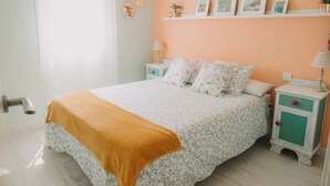 Ein Schlafzimmer mit einem Bett, Nachttischen, einem Regal mit Bildern und einem Fenster.