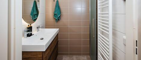 Un baño moderno con un tocador blanco, un espejo y dos toallas colgadas en la pared.