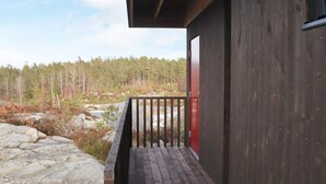 A wooden building with a wooden deck and a red door. - 6 Person Holiday Home in Sondeled (Risør)