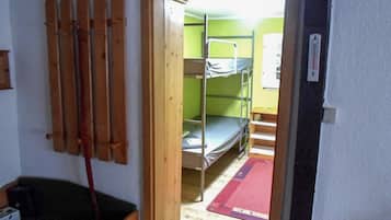 Een kamer met stapelbedden, een houten deur en een ski-rek.