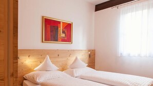 A double bed with a wooden headboard, white bedding, and a painting above it. - Sittnerhof Agriturismo - Apartment Goethe (Merano)