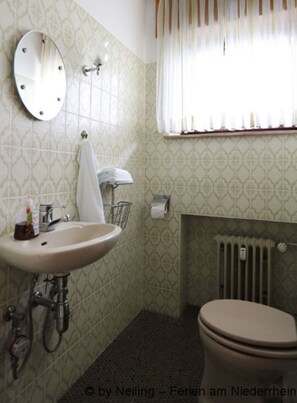 A bathroom with a sink, mirror, toilet, and radiator. - Pleasant Apartment in Xanten (Xanten)