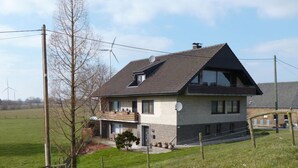 A two-story house with a sloped roof, satellite dish, and a fenced yard. - Pleasant Apartment in Xanten (Xanten)