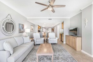 Uma sala de estar moderna com ventilador de teto, um sofá, uma mesa de centro e uma televisão.