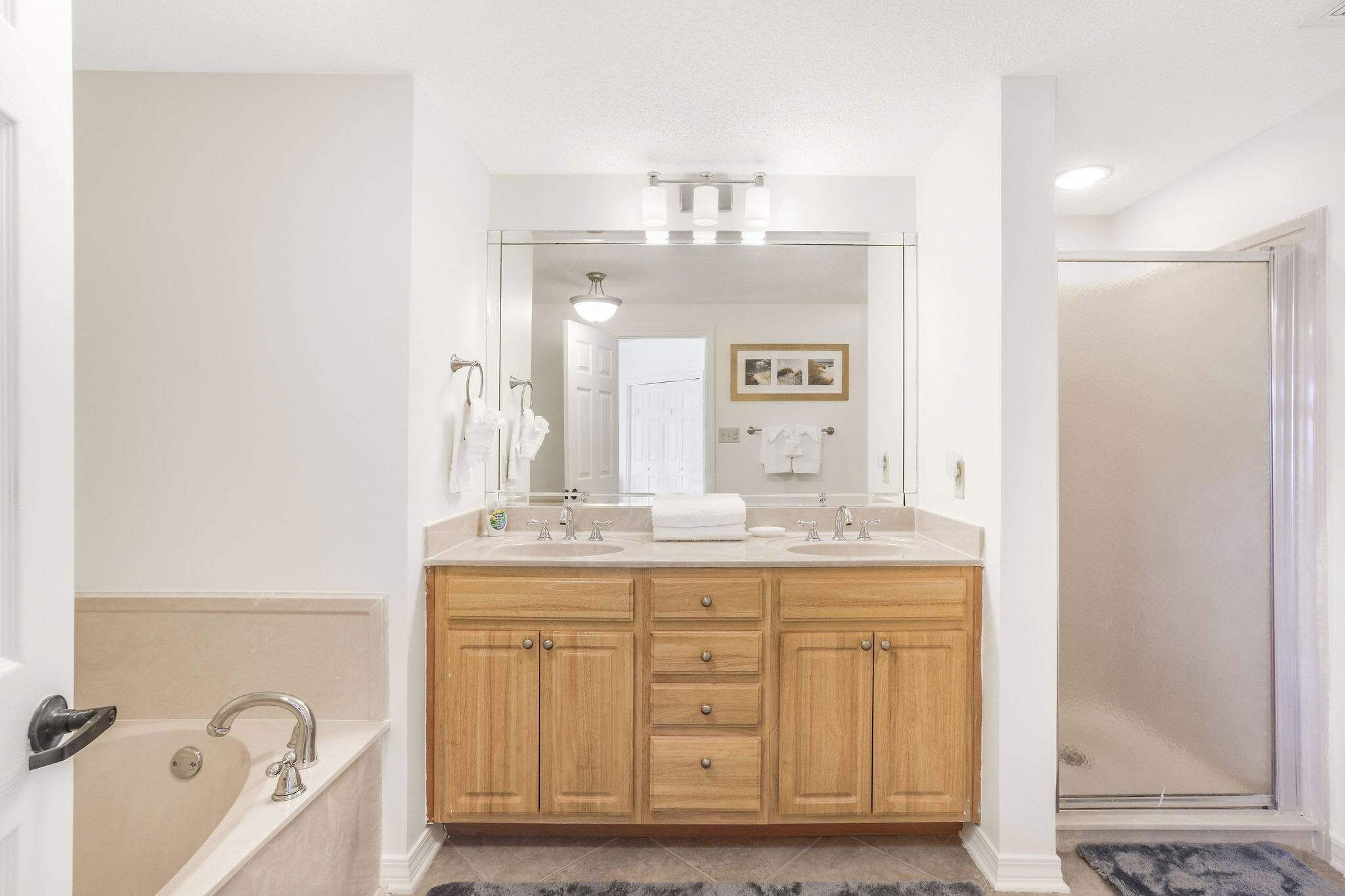 A bathroom with a double sink vanity, a bathtub, and a shower.