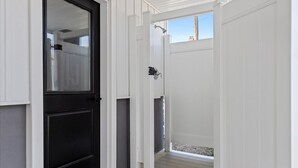 Una puerta blanca con un panel negro, un pequeño porche y vistas al exterior.