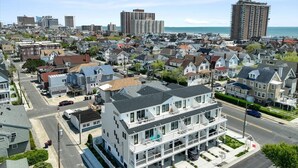 Un edificio residencial de varios pisos con balcón, situado en una zona urbana costera con vista al mar.