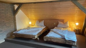 A cozy attic bedroom with two wooden beds, each with a nightstand and a lamp. - Rustic holiday home for 12 people (Warmensteinach)