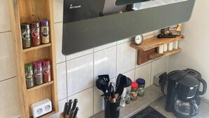 A kitchen with a black countertop, a wooden spice rack, a coffee maker, and a black range hood. - Rustic holiday home for 12 people (Warmensteinach)