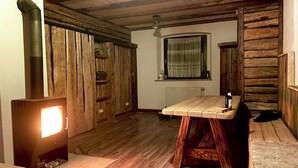 A rustic wooden interior with a central wooden table, a built-in bench, and a fireplace with a visible chimney. - Rustic holiday home for 12 people (Warmensteinach)