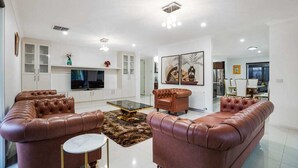 Una sala de estar moderna con sofás de cuero, una mesa de centro de vidrio y un televisor de pantalla plana.