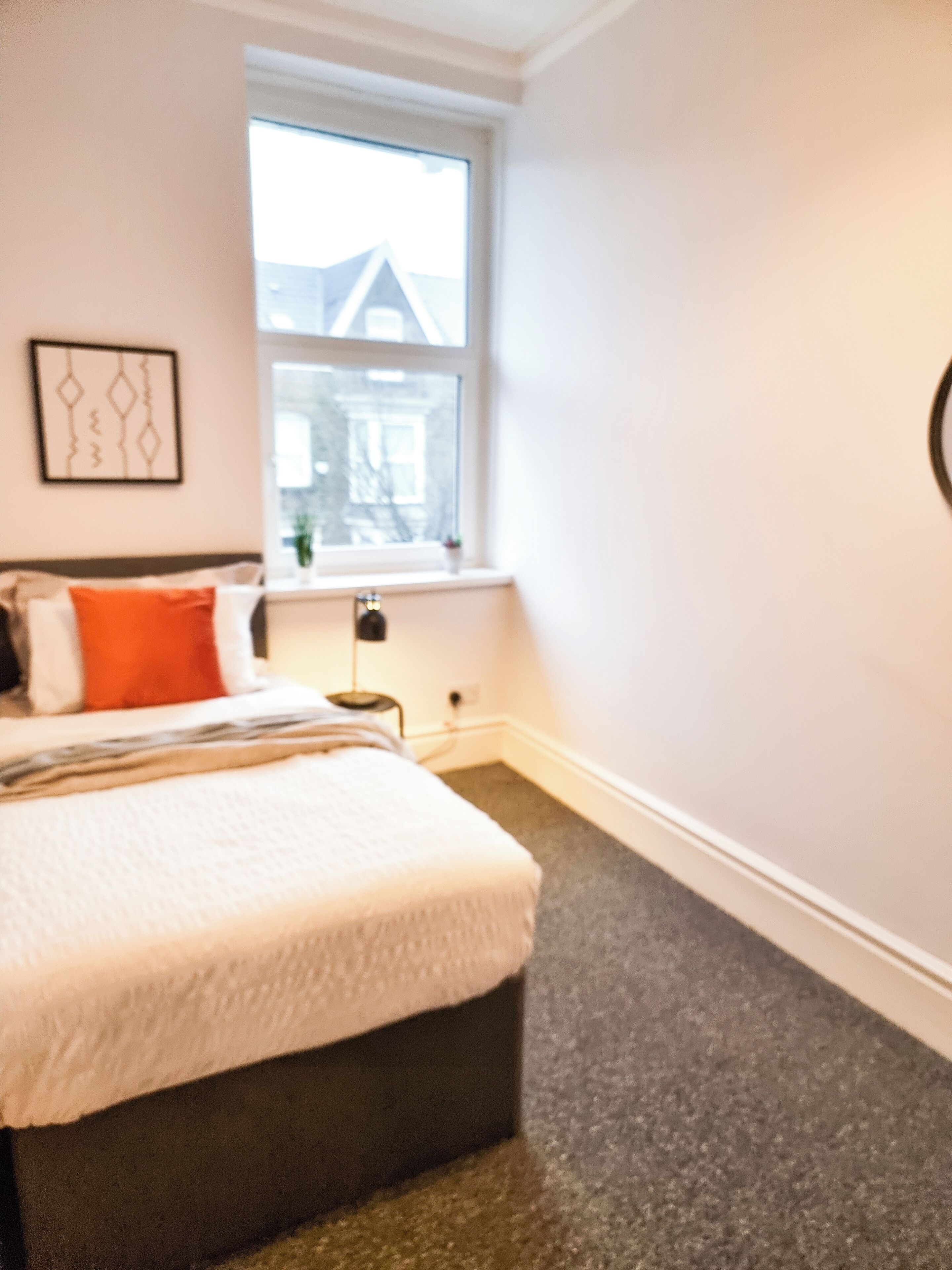 Une chambre à coucher avec un lit, une fenêtre et un tableau accroché au mur.