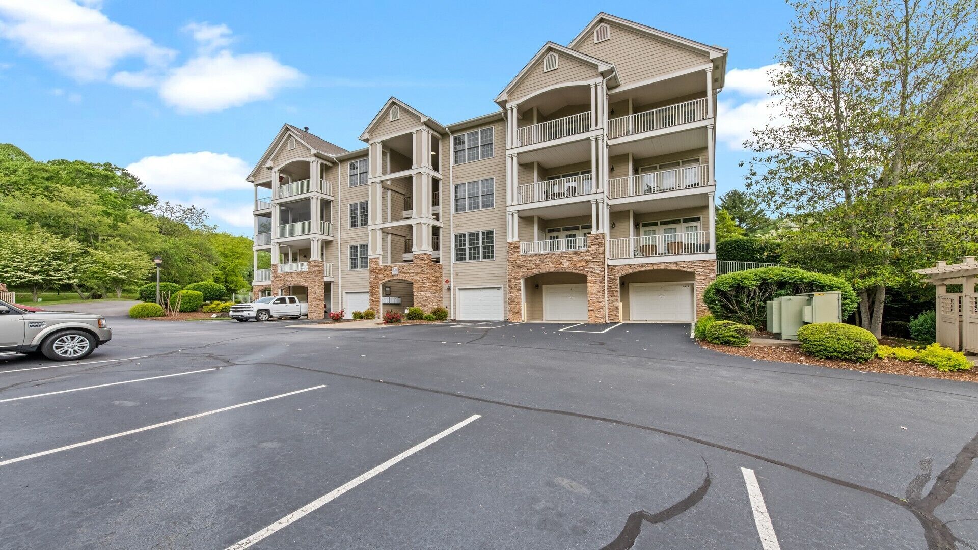 A multi-story hotel with a stone facade, multiple balconies, and a parking lot.