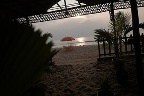 Une vue sur la plage avec une pergola en bois, une table avec des chaises et un parasol de plage.
