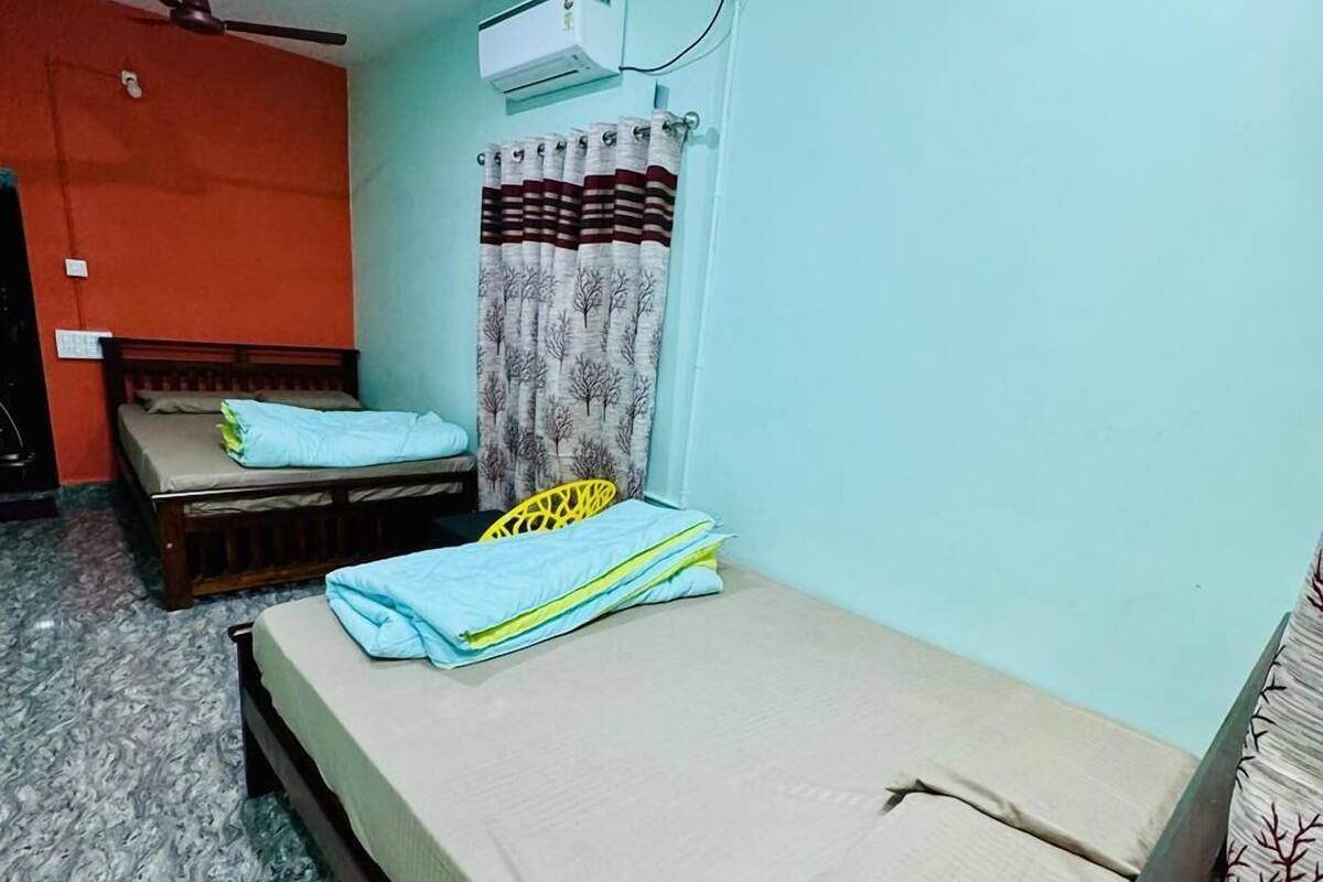 Ein Zimmer mit zwei Betten, einem Deckenventilator, einer Klimaanlage und einem Vorhang.