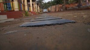 Een pad met trappen leidt naar een gebouw met kleurrijke relingen, en een auto staat in de buurt geparkeerd.