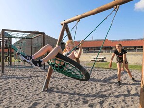 Un parque infantil con columpios y una estructura para escalar.