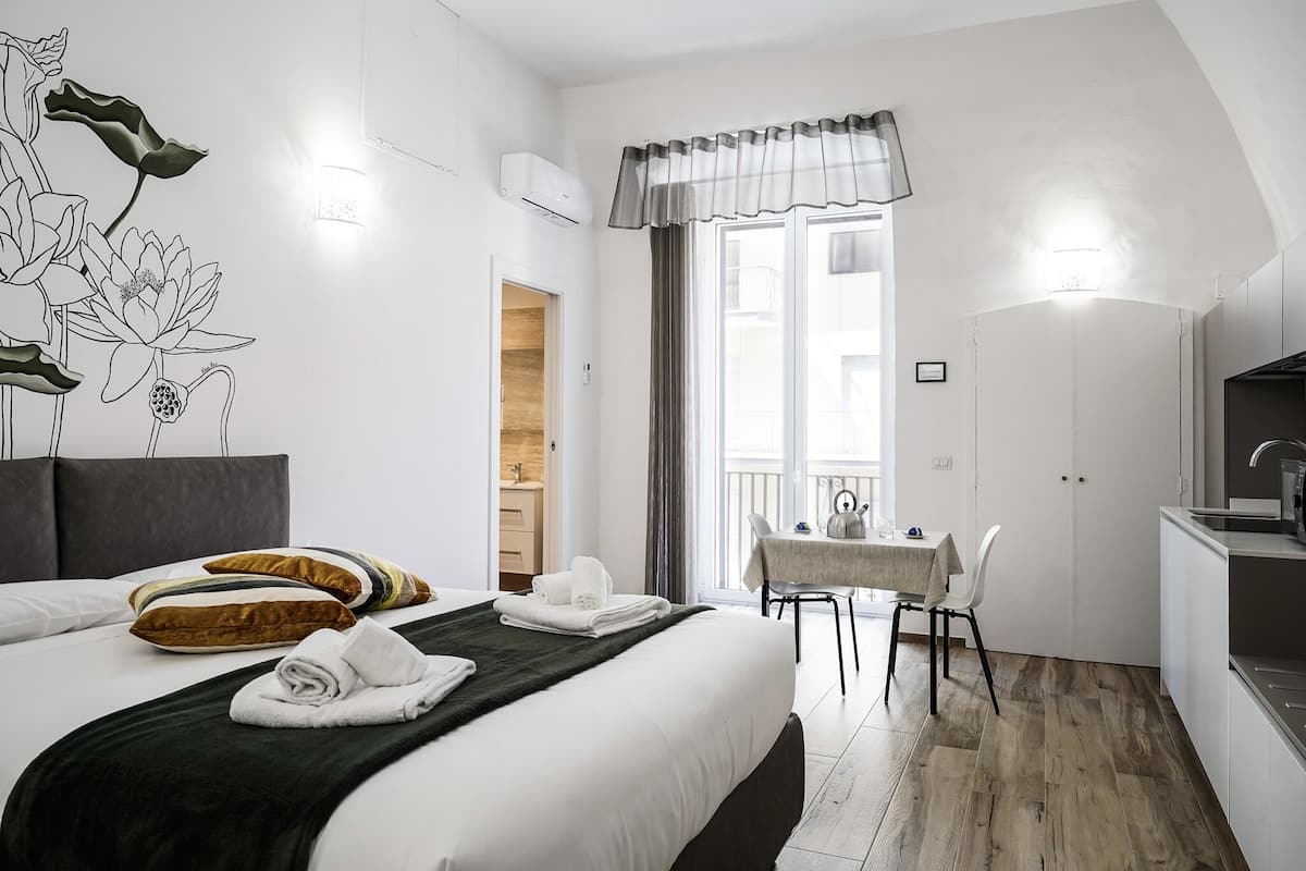Una camera d'albergo con un letto, un tavolo da pranzo, angolo cottura e un balcone con vista.