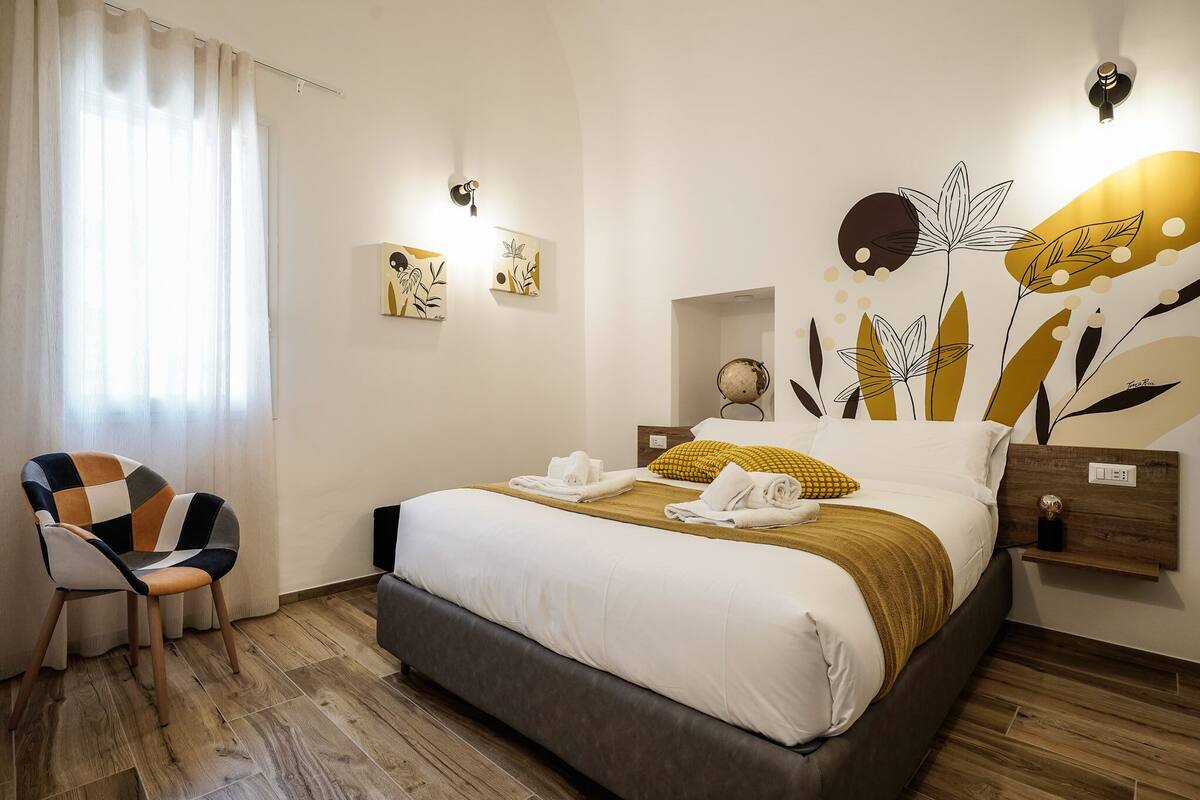 Una camera d'albergo con un letto, una sedia e opere d'arte alle pareti.