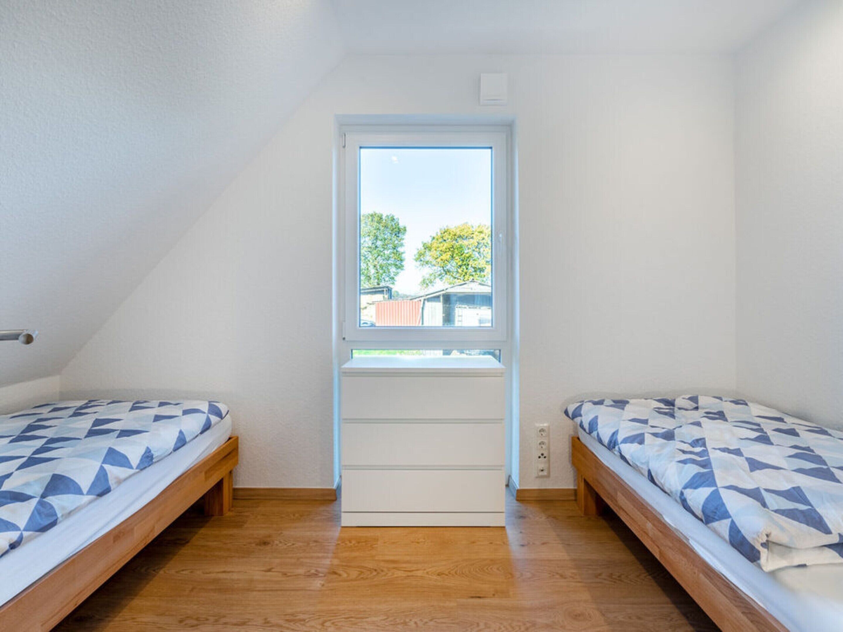 A small, single-room apartment with two beds, a window, and a door.