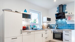 Een moderne keuken met witte kastjes, een ingebouwde oven en een blauwe achterwand.