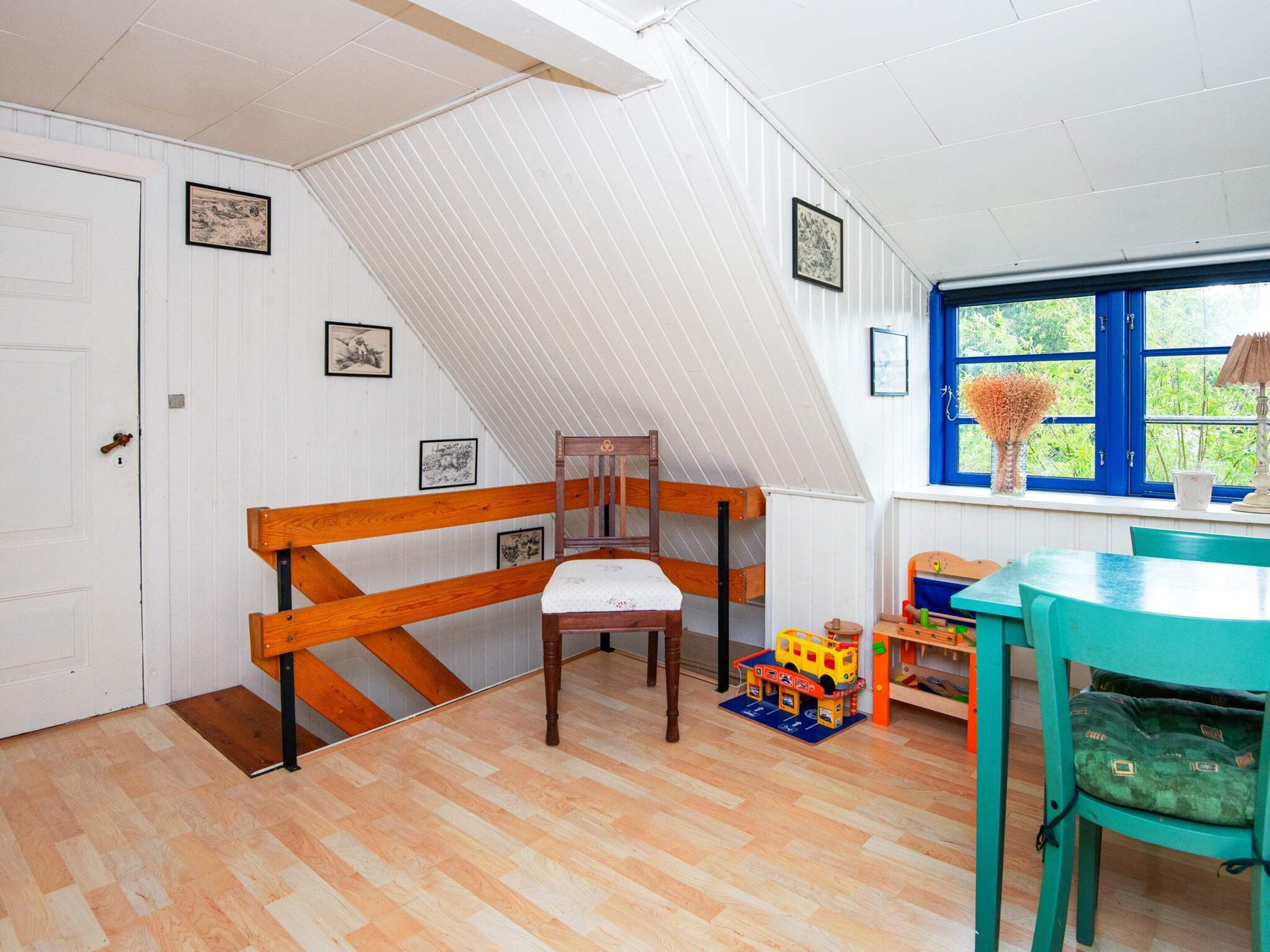 Una stanza con un letto a soppalco, una sedia in legno, un tavolo e una finestra vista sul verde.