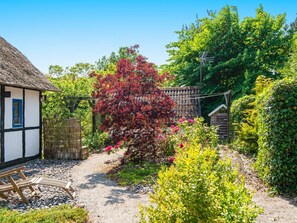 A traditional thatched-roof cottage with a gravel path leading to a wooden bench. - 6 Person Holiday Home in Orsted (Ørsted)