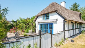 Une maison traditionnelle avec un toit de chaume, des murs blancs et des touches de couleur bleue.