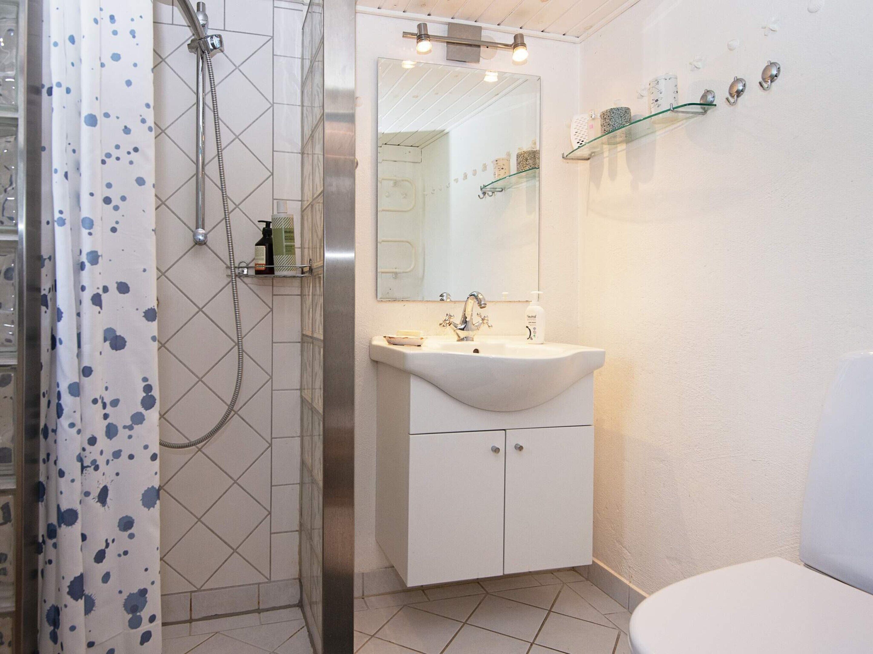 Ein Badezimmer mit Dusche, Waschbecken, Spiegel und Toilette.