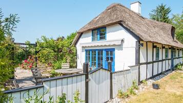 A traditional house with a thatched roof, white walls, and blue doors.
