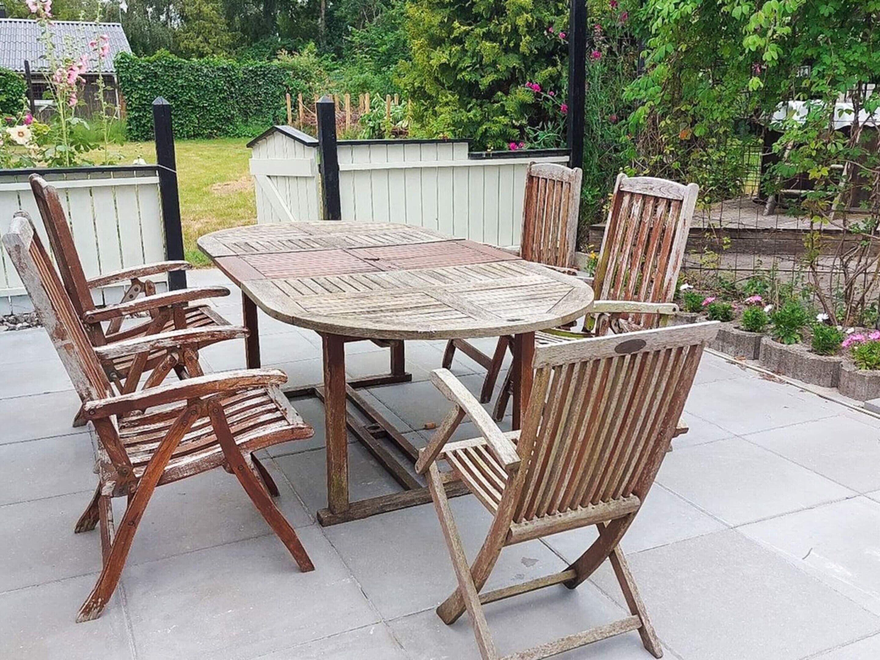 An outdoor patio with a round wooden table and six wooden chairs.