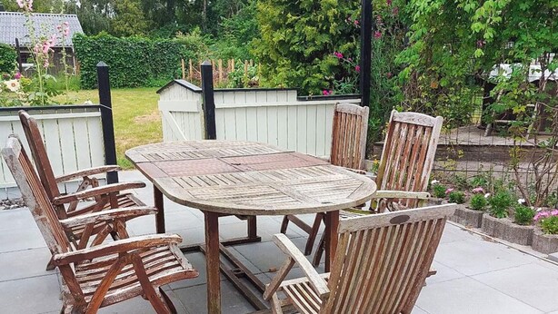 An outdoor patio with a round wooden table and six wooden chairs. - 6 Person Holiday Home in Orsted (Ørsted)
